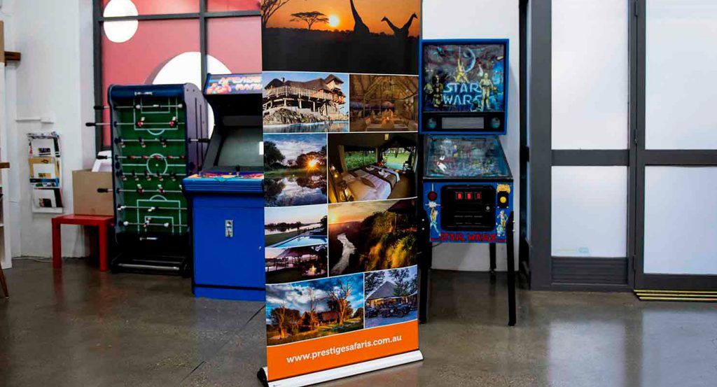 Prestige Safaris pull-up banner with full-colour safari photo collage and orange URL strip, standing in a studio.